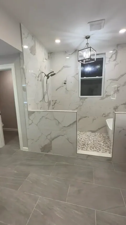 Bathroom with tiled shower pony walls, mosaic floor, and bathtub edge