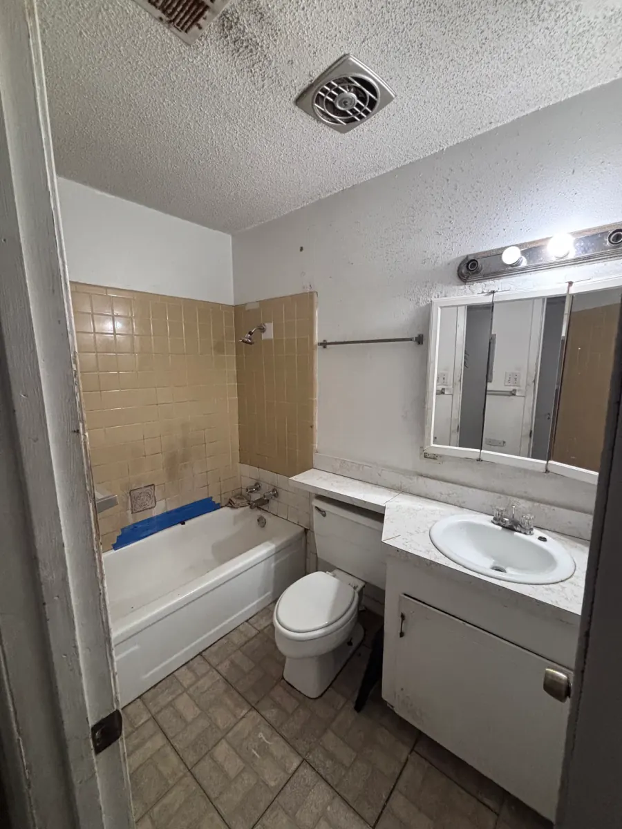 Original bathroom with a bathtub, small square surround tile, vanity, toilet, and doorway clearances