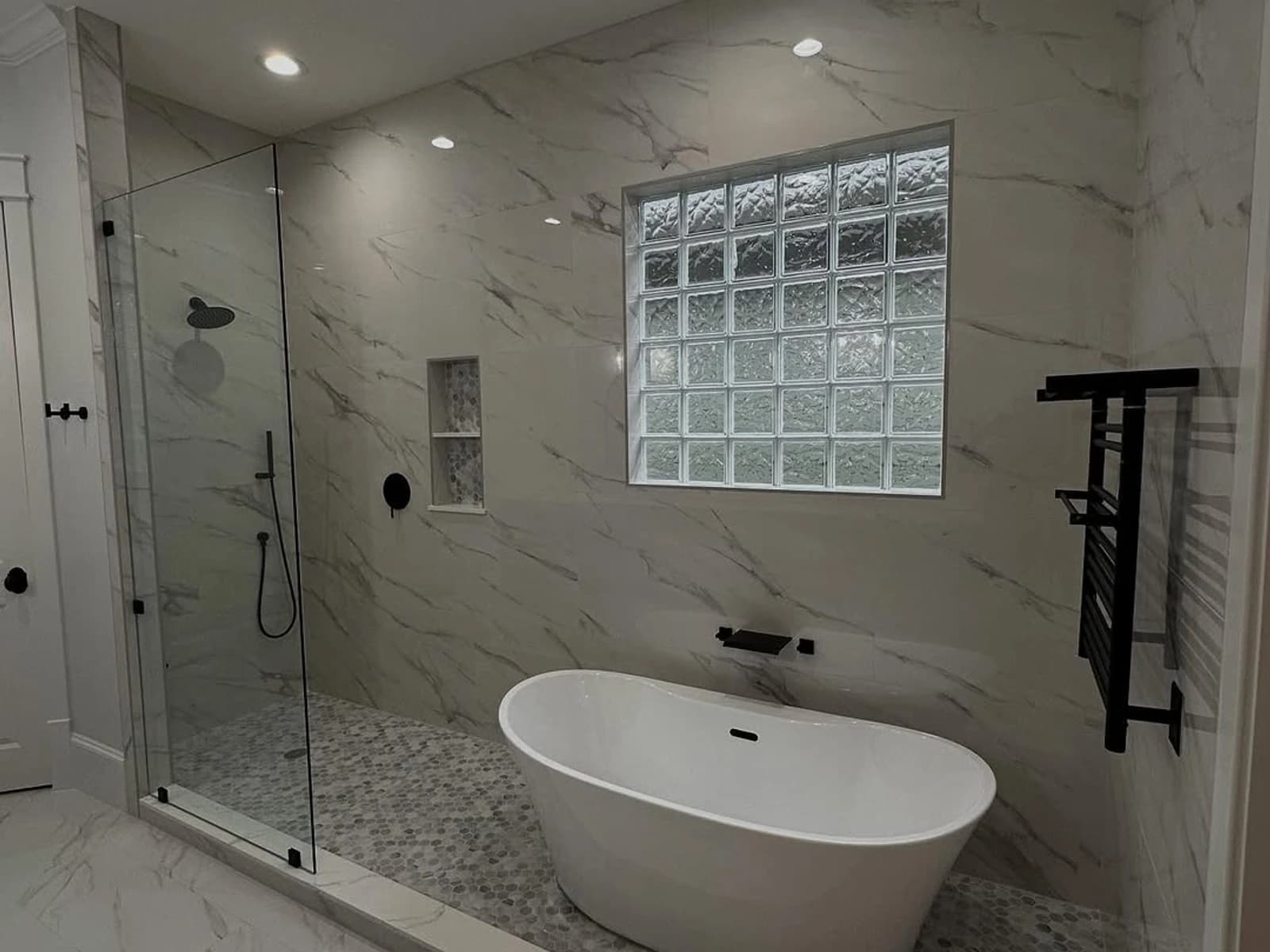 Finished tub and glass shower bathroom with marble-look tile and glass block window