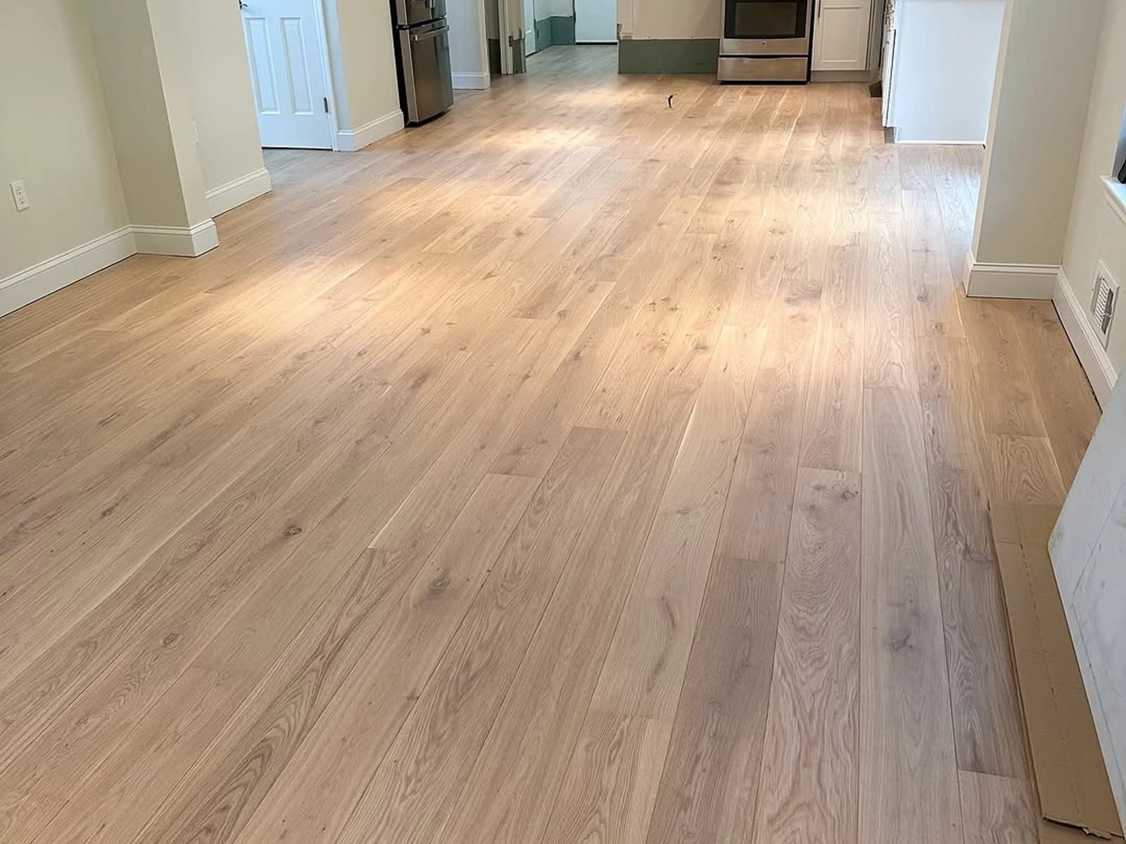 Kitchen and dining flooring installation with light wood-look planks and white cabinets
