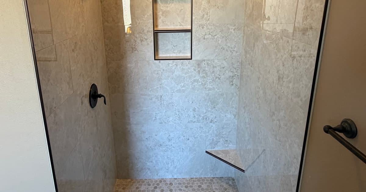 Custom tile shower conversion in East Texas with light wall tile, recessed niche, mosaic floor, and black shower hardware