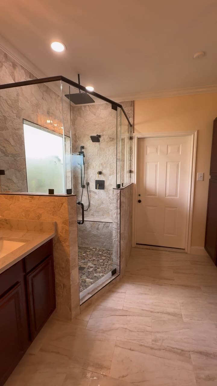 Bathroom layout remodel in Tyler TX with freestanding tub, glass shower, pony wall, tile floor, and vanity by Pioneer Construction