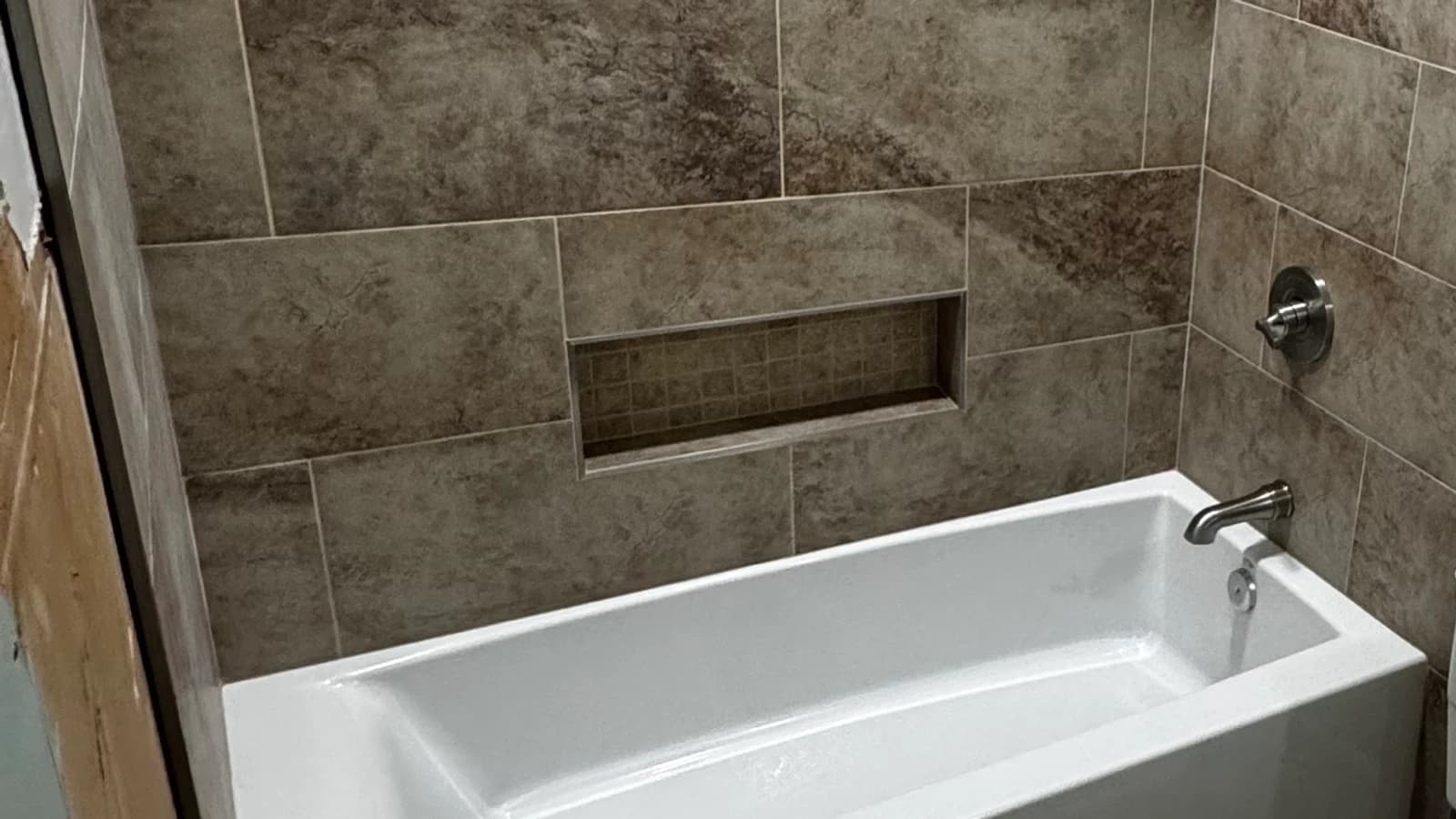 Finished tiled tub-and-shower surround with a recessed niche above a new white bathtub in Tyler TX