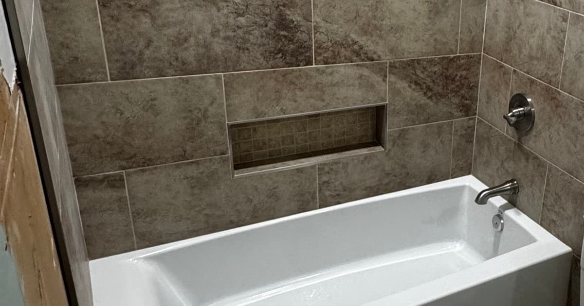 Finished tiled tub-and-shower surround with a recessed niche above a new white bathtub in Tyler TX